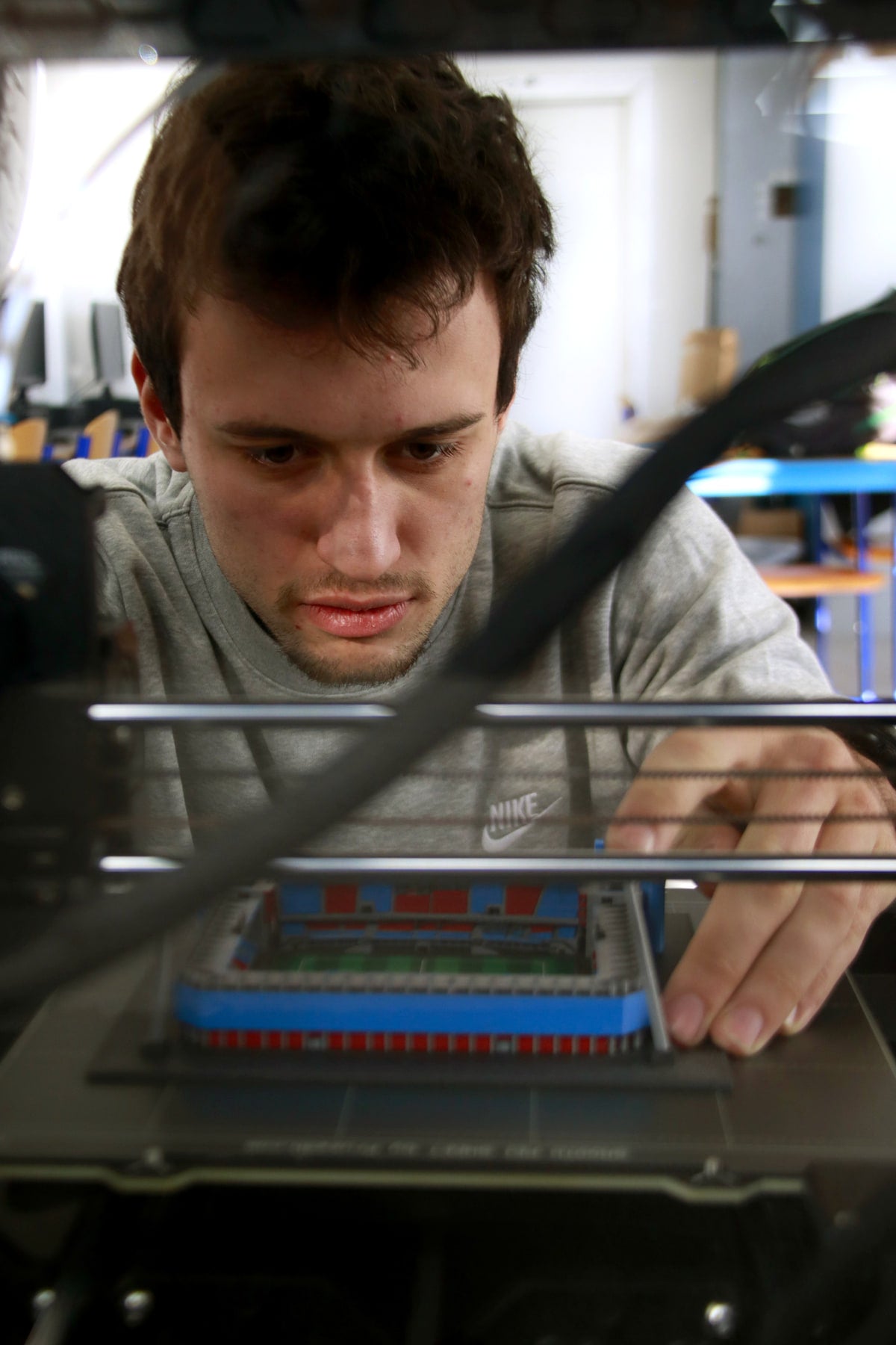 Original photograph of Petr reviewing a finished stadium model inside the printer
